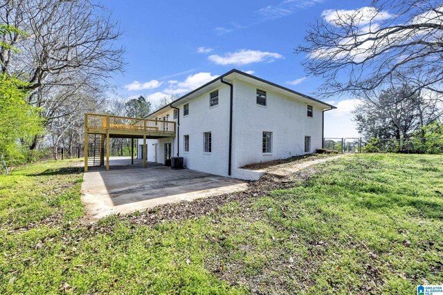 view of side of property featuring a deck, a patio, central air condition unit, fence, and a yard