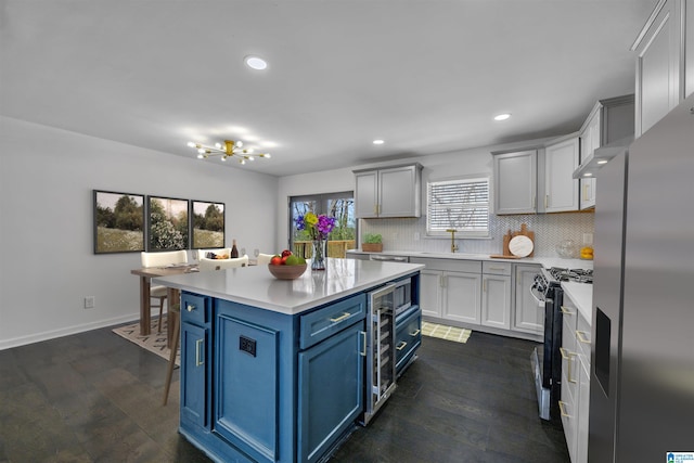 kitchen featuring a center island, decorative backsplash, appliances with stainless steel finishes, dark hardwood / wood-style flooring, and blue cabinets