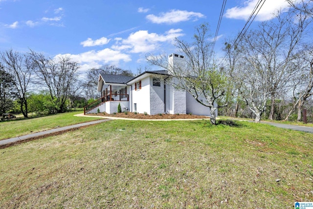 view of front of home with stairs, a front lawn, and a chimney