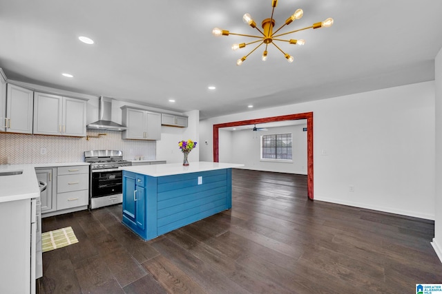 kitchen featuring dark hardwood / wood-style flooring, a kitchen island, hanging light fixtures, gas range, and wall chimney range hood