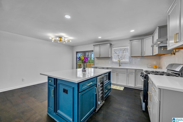 kitchen featuring blue cabinetry, a center island, decorative backsplash, dark wood-type flooring, and gas range