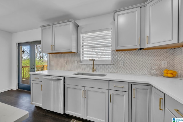 kitchen with stainless steel dishwasher, dark wood-type flooring, sink, gray cabinets, and decorative backsplash