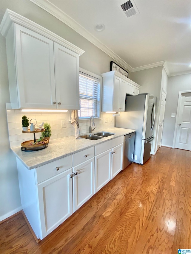 kitchen with sink, light wood-type flooring, tasteful backsplash, white cabinetry, and stainless steel appliances