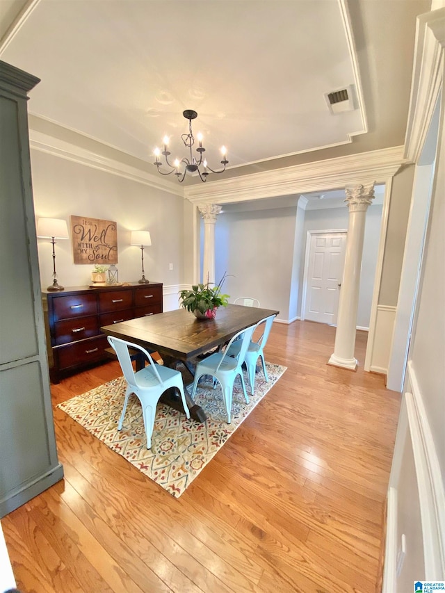 dining room featuring an inviting chandelier, ornate columns, crown molding, and light hardwood / wood-style flooring