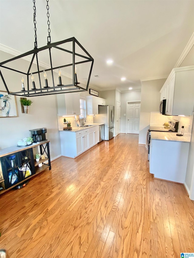 living room with ornamental molding, light wood-type flooring, a notable chandelier, and sink