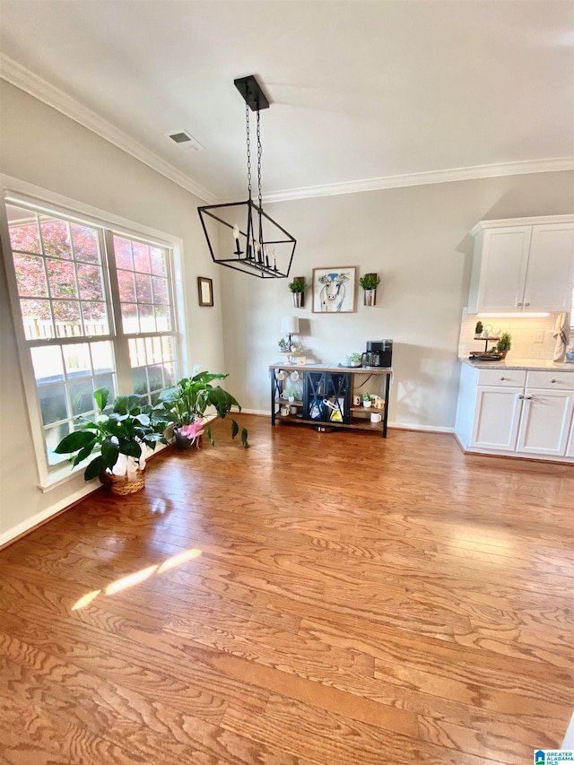 dining area featuring light hardwood / wood-style flooring, an inviting chandelier, and ornamental molding