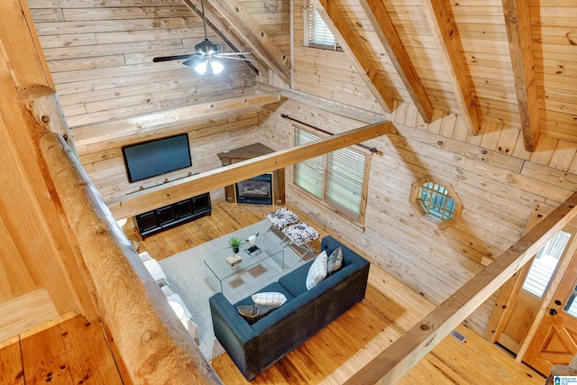 living room with wood walls, ceiling fan, vaulted ceiling with beams, wood ceiling, and hardwood / wood-style floors