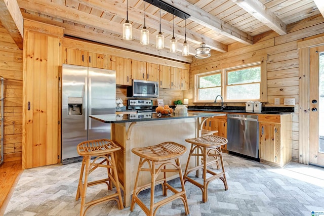 kitchen with beamed ceiling, appliances with stainless steel finishes, a kitchen island, wood ceiling, and pendant lighting