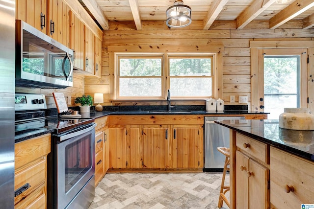 kitchen with appliances with stainless steel finishes, sink, dark stone counters, beam ceiling, and wooden ceiling