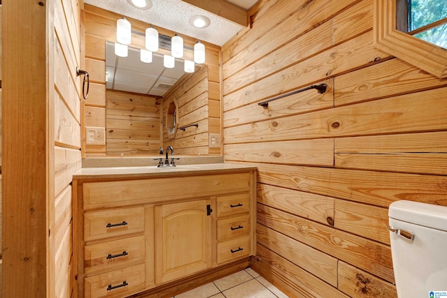 bathroom with tile flooring, a paneled ceiling, toilet, wood walls, and vanity