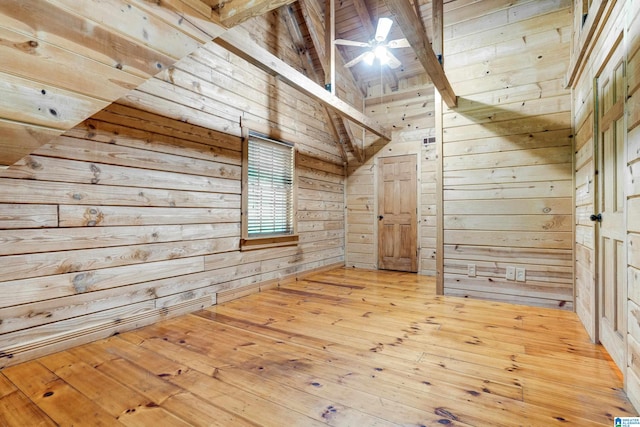 additional living space featuring wood walls, light hardwood / wood-style floors, beam ceiling, and high vaulted ceiling