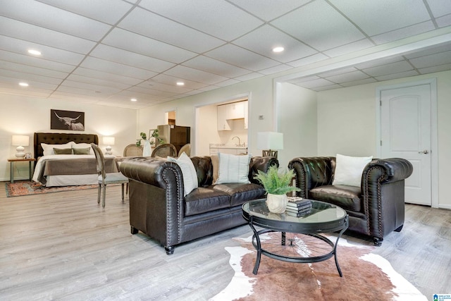 living room with light hardwood / wood-style floors and a paneled ceiling