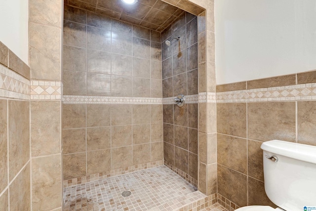 bathroom featuring tiled shower, tile walls, and toilet