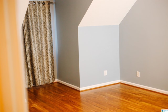 additional living space with hardwood / wood-style flooring and vaulted ceiling