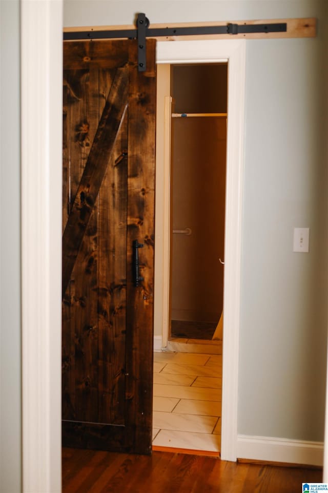 hallway with wood-type flooring and a barn door