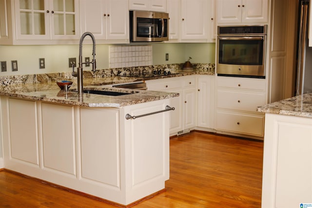 kitchen with appliances with stainless steel finishes, light stone countertops, and white cabinets