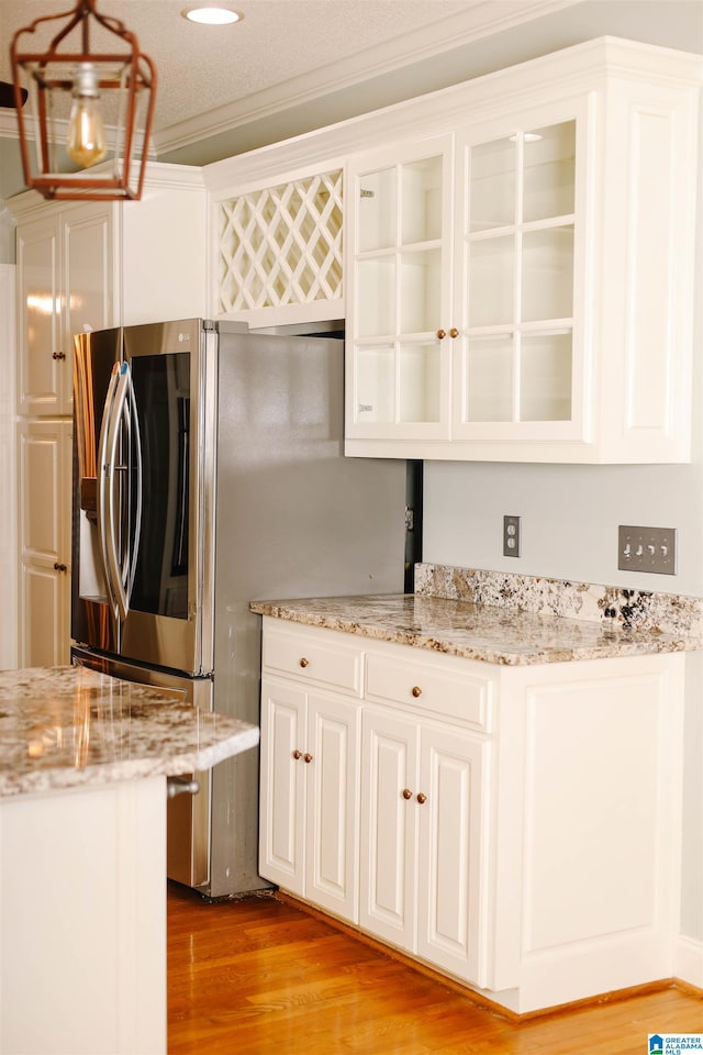 kitchen featuring crown molding, light stone counters, light hardwood / wood-style flooring, hanging light fixtures, and white cabinets