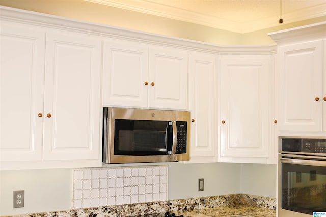 kitchen featuring white cabinetry, crown molding, light stone countertops, and appliances with stainless steel finishes