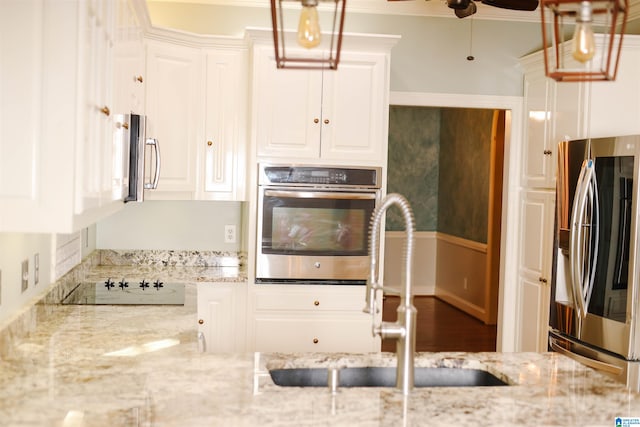 kitchen featuring sink, ceiling fan, appliances with stainless steel finishes, light stone countertops, and white cabinets