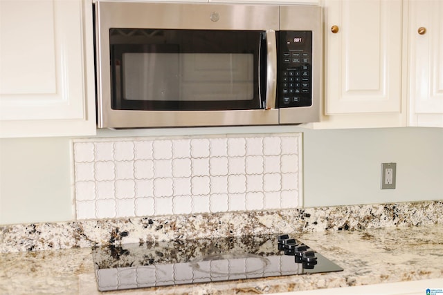 room details with light stone counters, black electric stovetop, and white cabinets