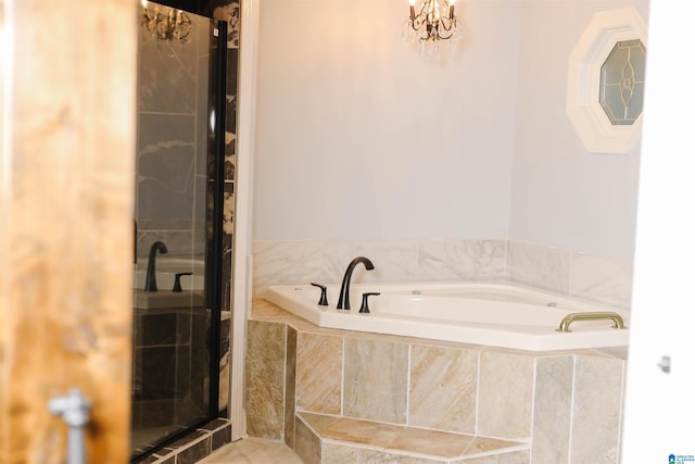 bathroom featuring a relaxing tiled tub and a chandelier