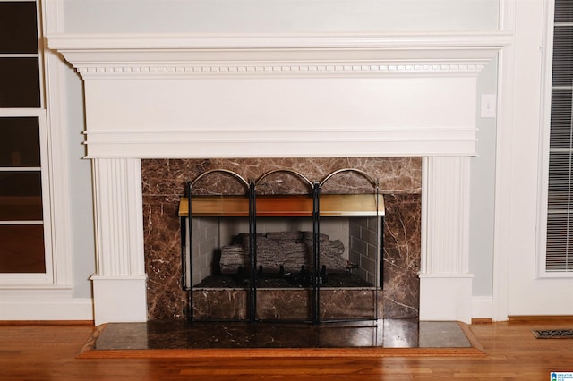 interior details featuring wood-type flooring and a stone fireplace