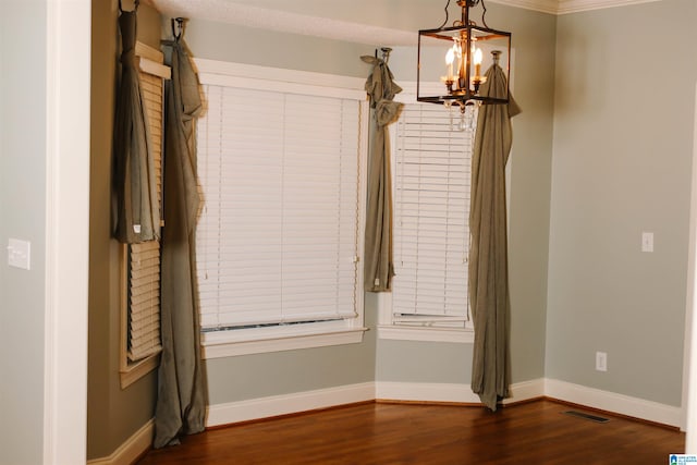 empty room with an inviting chandelier, ornamental molding, and dark hardwood / wood-style floors