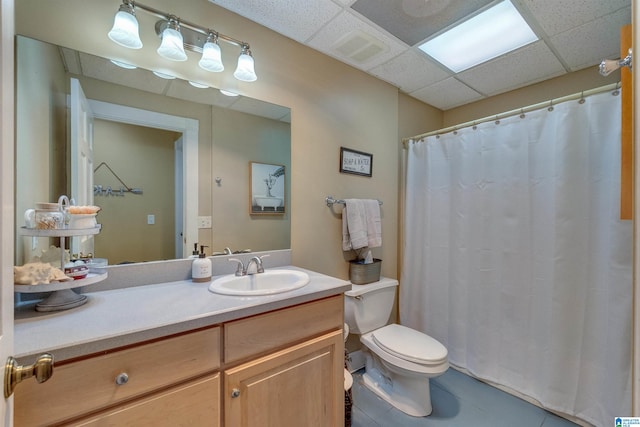 bathroom featuring tile flooring, a paneled ceiling, toilet, and vanity