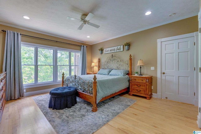 bedroom featuring a textured ceiling, ceiling fan, light wood-type flooring, and crown molding