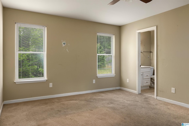 unfurnished bedroom featuring light colored carpet, ceiling fan, and ensuite bathroom