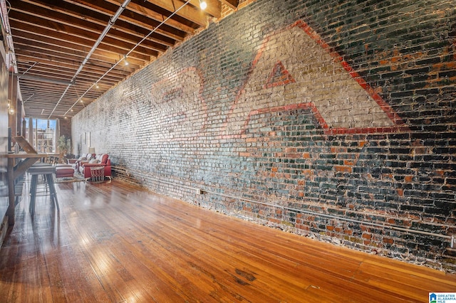 interior space with hardwood / wood-style flooring and brick wall