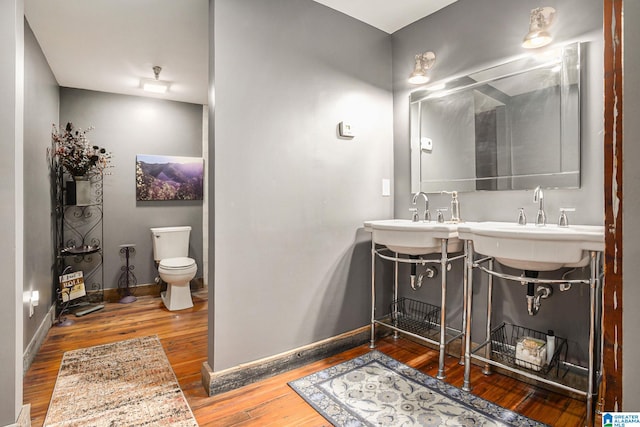 bathroom featuring dual vanity, toilet, and wood-type flooring