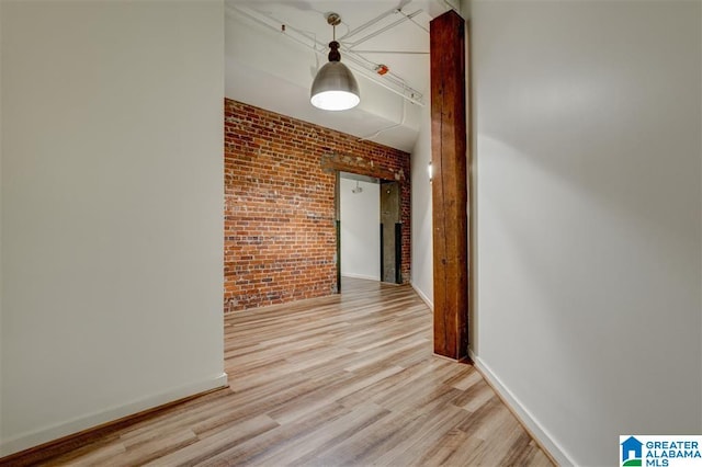 corridor with brick wall and light wood-type flooring