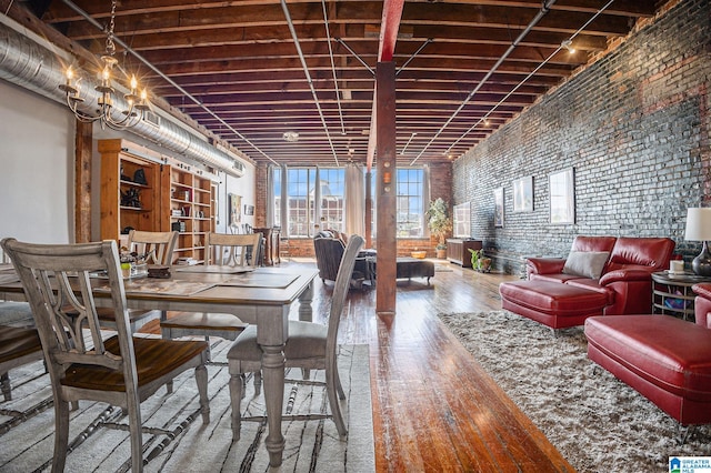 dining space featuring brick wall, a chandelier, and hardwood / wood-style flooring