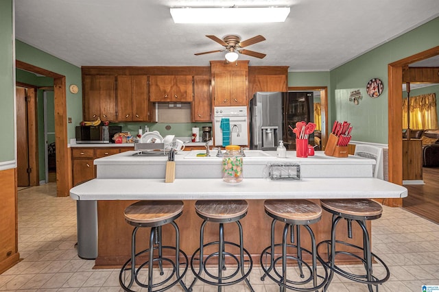 kitchen featuring ceiling fan, light tile floors, stainless steel appliances, and a breakfast bar