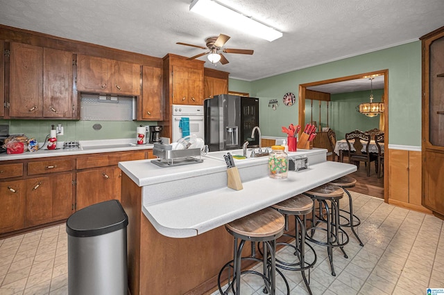 kitchen with ceiling fan with notable chandelier, oven, black fridge, and light tile flooring