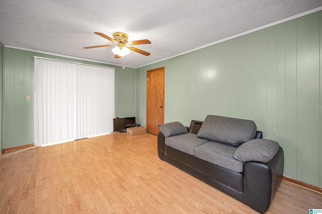 living room featuring ornamental molding, light hardwood / wood-style flooring, ceiling fan, and a textured ceiling