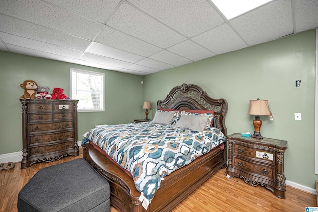 bedroom with hardwood / wood-style floors and a paneled ceiling