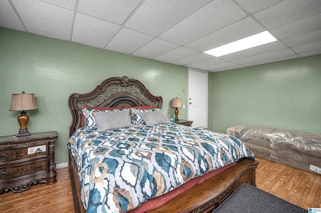 bedroom featuring a drop ceiling and hardwood / wood-style floors