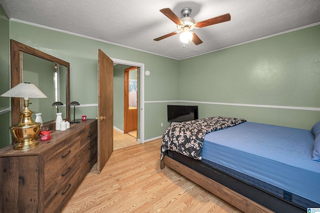 bedroom featuring ornamental molding, light hardwood / wood-style flooring, ceiling fan, and a textured ceiling