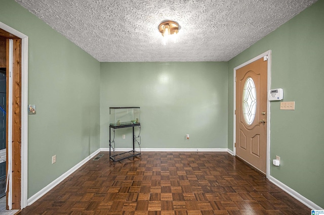 entrance foyer featuring dark parquet flooring and a textured ceiling