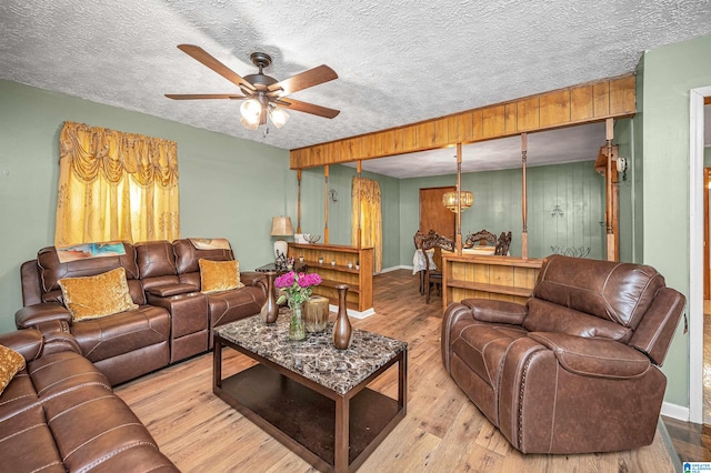 living room featuring light hardwood / wood-style flooring, ceiling fan, and a textured ceiling