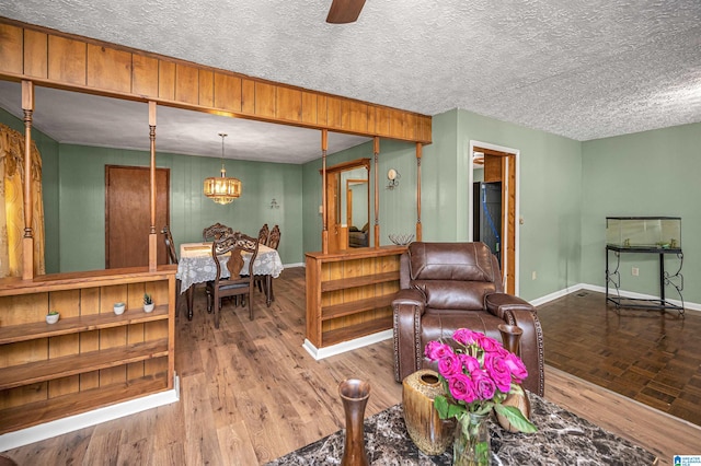 living room featuring parquet flooring, a textured ceiling, and ceiling fan with notable chandelier