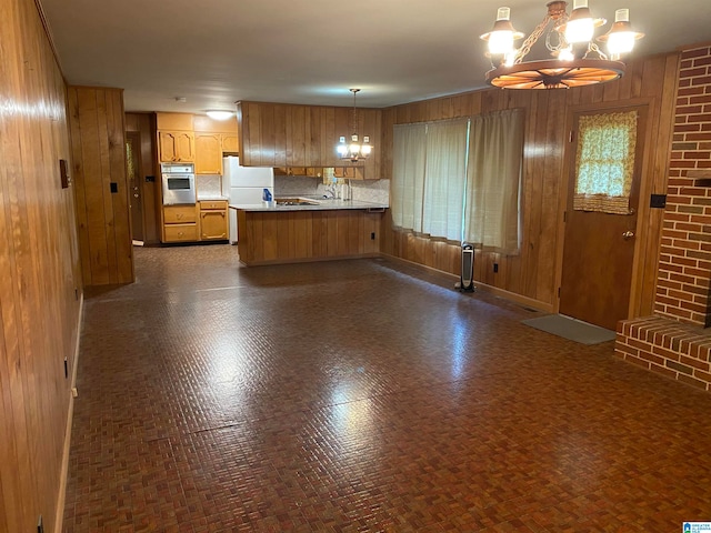 kitchen featuring a notable chandelier, kitchen peninsula, oven, white fridge, and pendant lighting