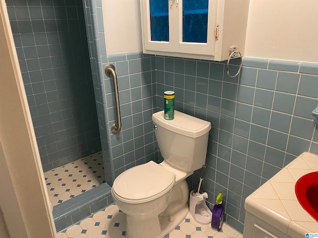 bathroom with tile patterned floors, toilet, a tile shower, and tile walls