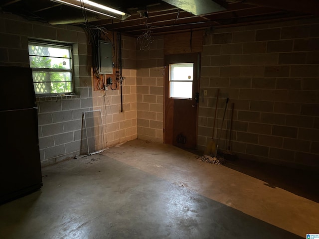 basement with electric panel and black refrigerator