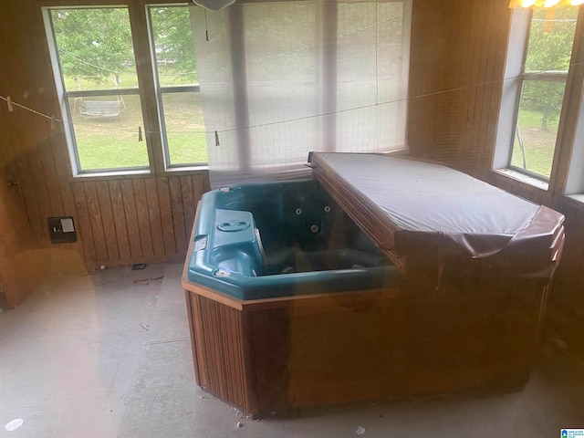 interior space with a hot tub, plenty of natural light, and wood walls