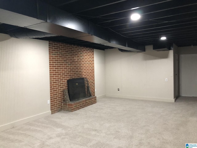 basement featuring light colored carpet and a fireplace