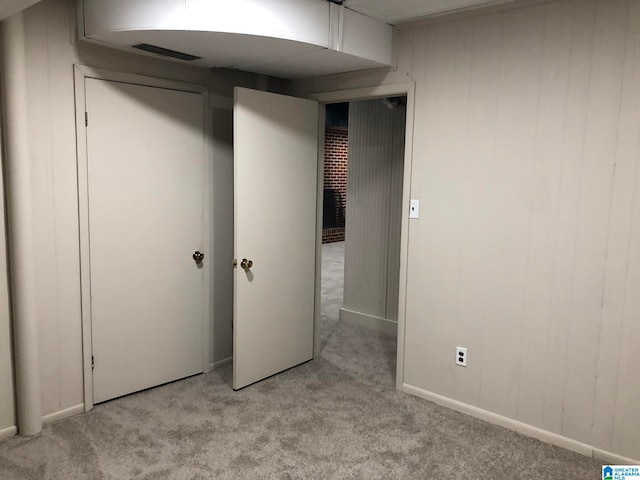 unfurnished bedroom featuring wooden walls and light colored carpet