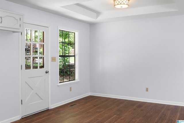 interior space with a tray ceiling and dark wood-type flooring